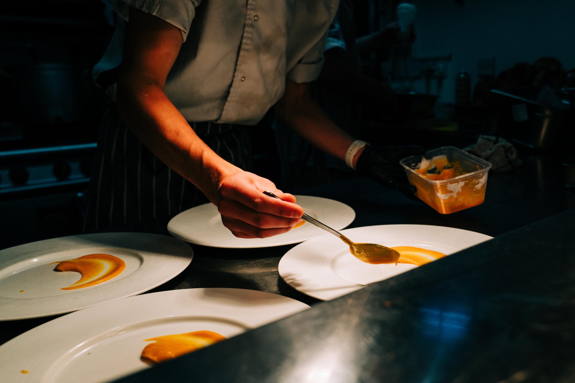 Sauce being finished on plates in the kitchen