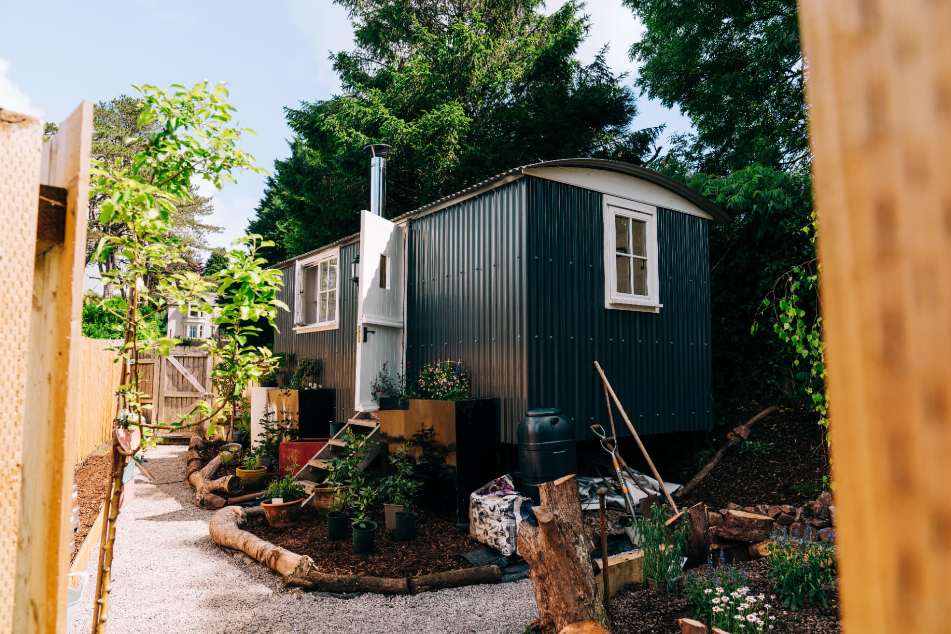 Gravel path leading to the shepherd's hut among trees and planting