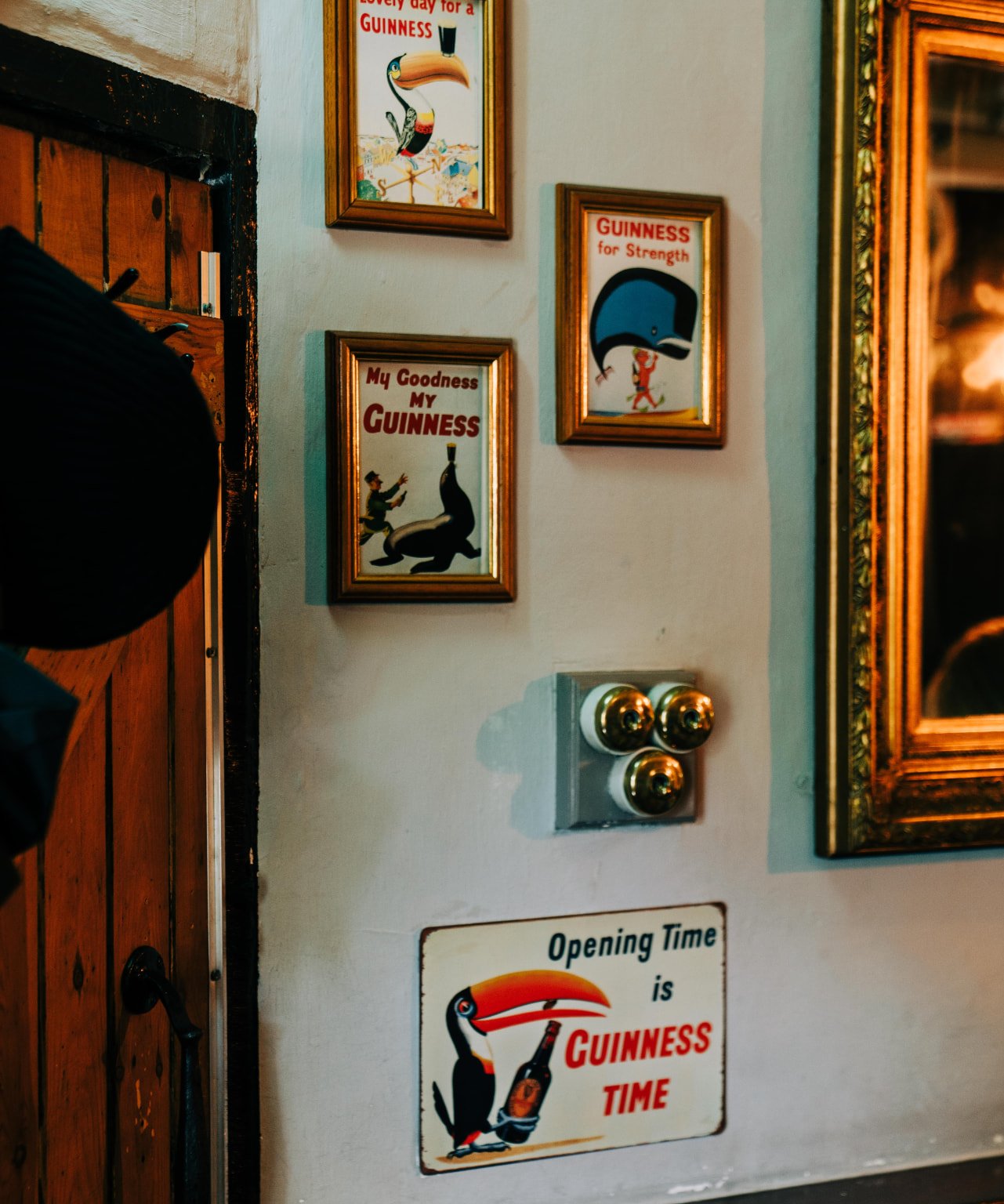 Framed vintage Guinness posters beside a gilt mirror