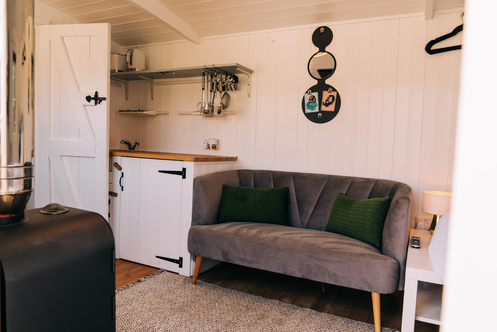 Grey sofa with green cushions beside the kitchenette